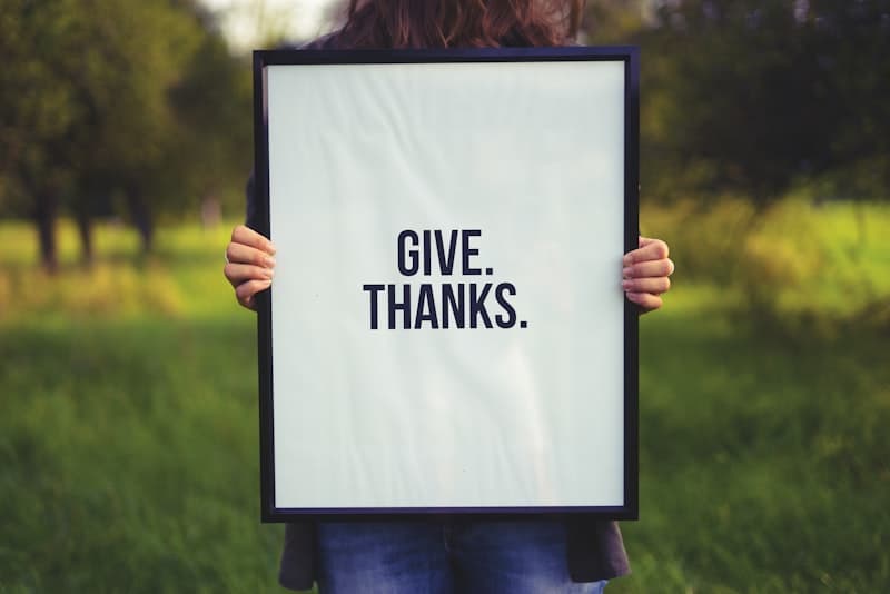 Person holding a photo frame with Give. Thanks. print